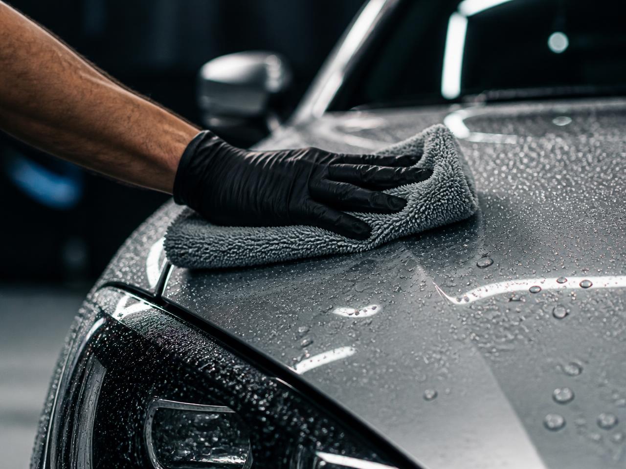 Detailer hand washing and drying a car hood during exterior car detailing in Millbrae